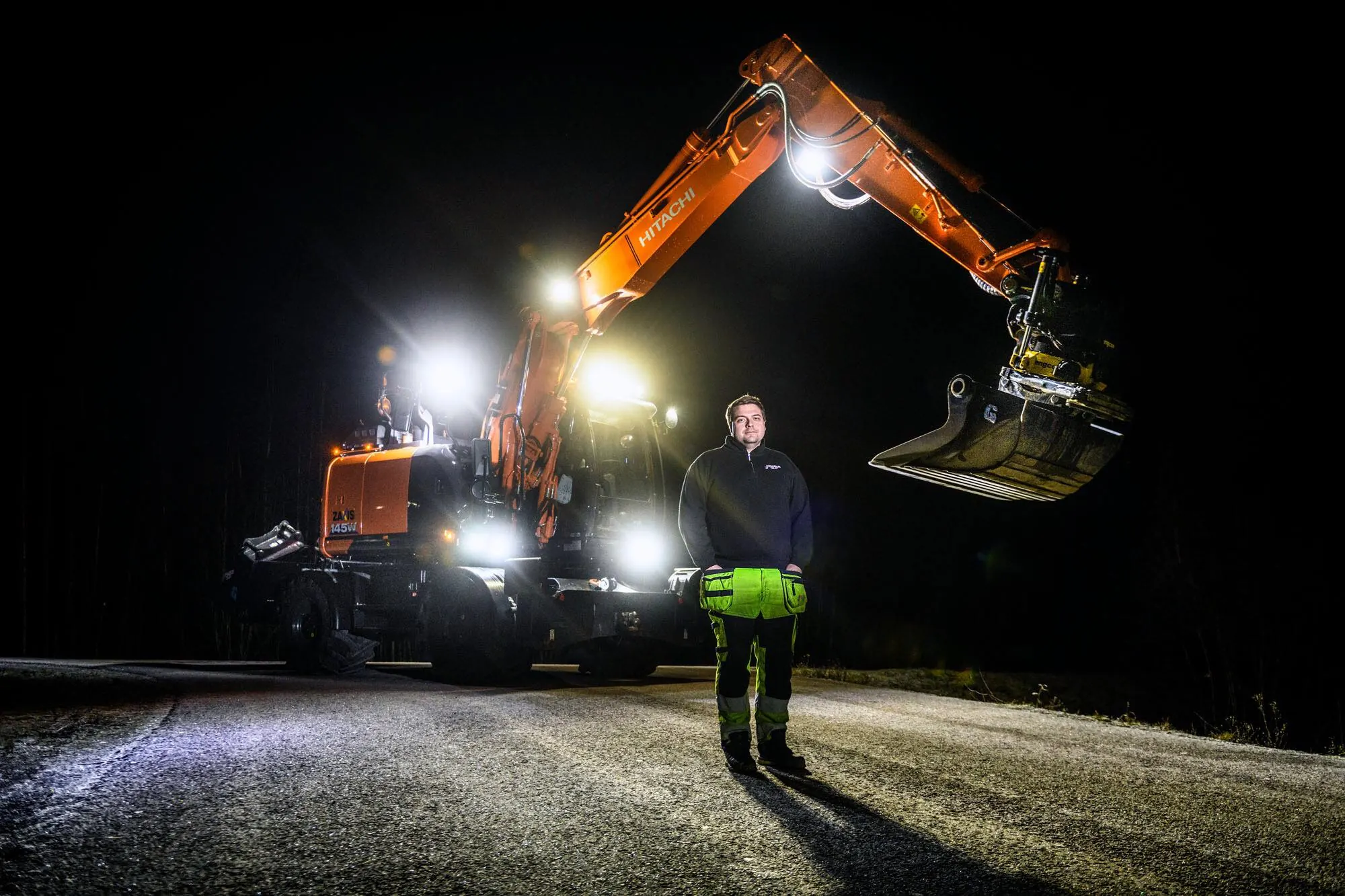 Jonasson Grävs hjulgrävare Hitachi 145 på kvällsjobb med arbetsbelysningen tänd